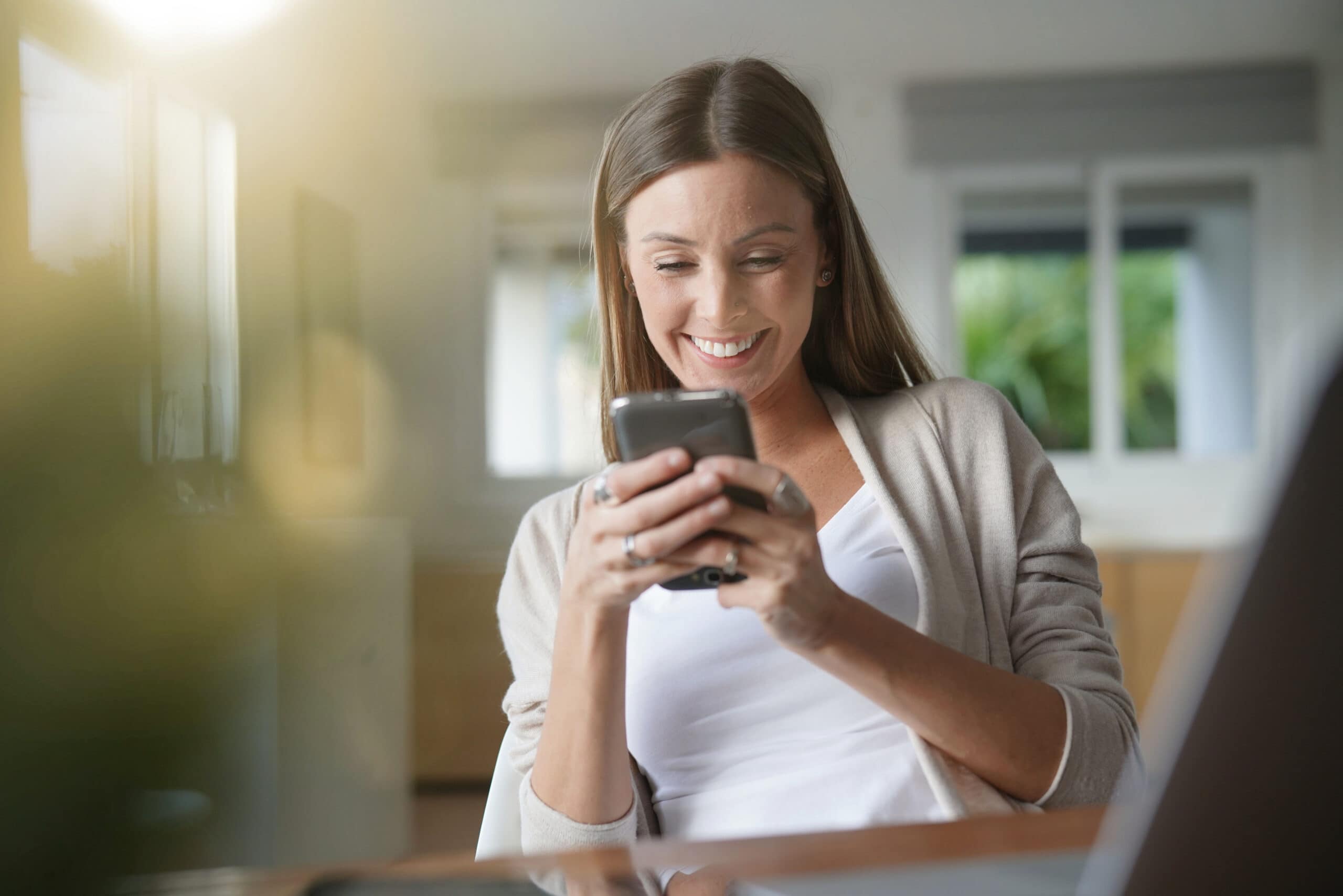 Frau schaut lächelnd auf ihr Smartphone